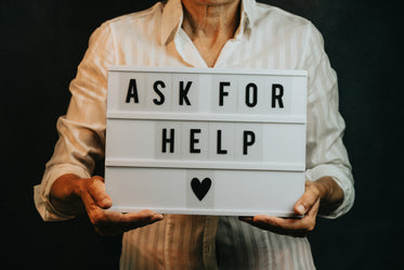 person holds a sign that says ask for help