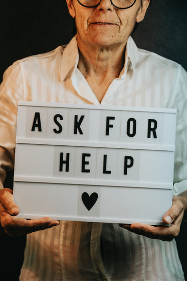 person holds a sign with message ask for help