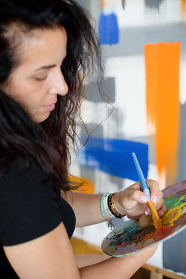 person holds brush to a pallet while painting