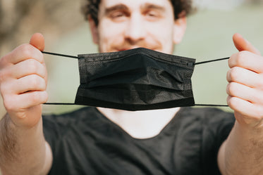 person holds out a black facemask