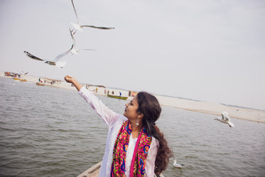 person holds out hand to feed the birds overhead