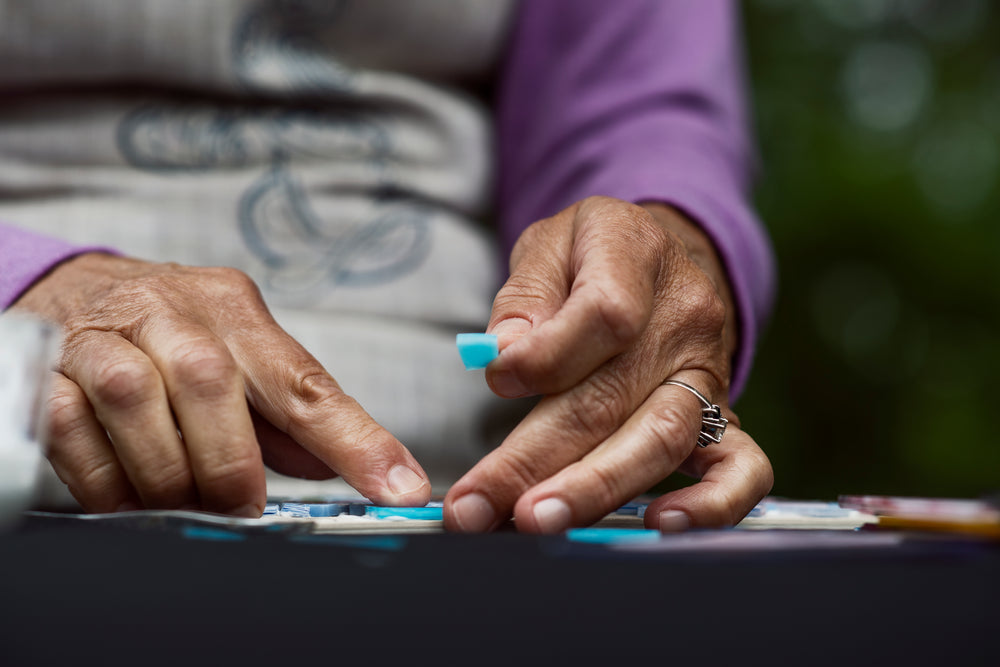 person holds small piece of blue glass to place into a mosaic