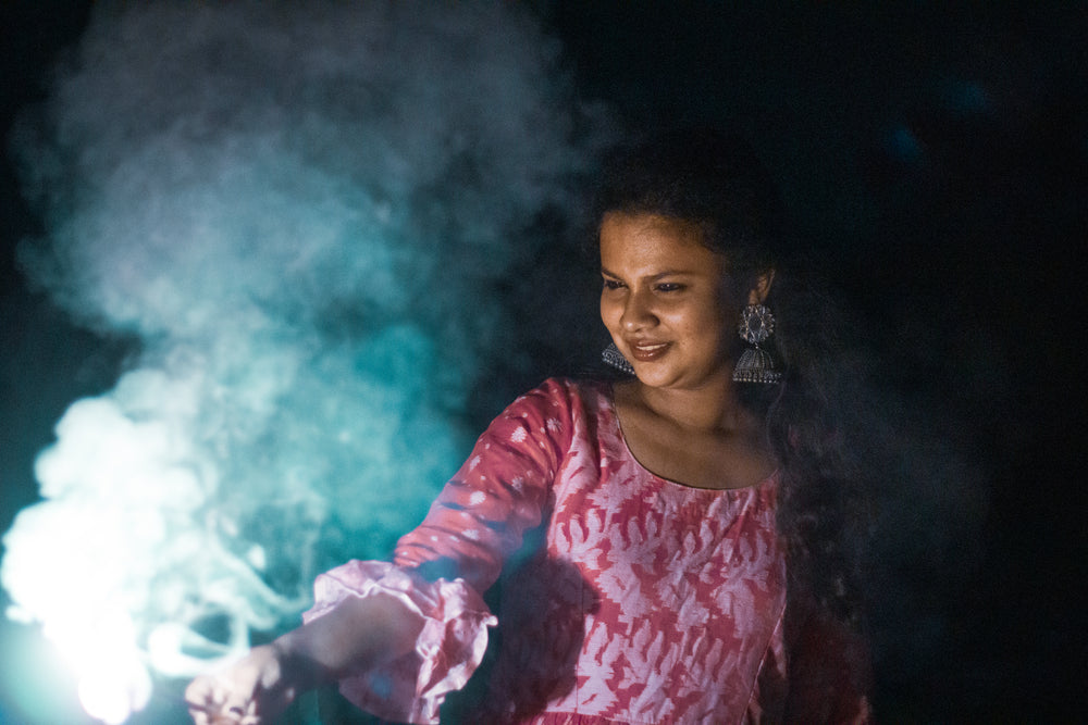 person holds sparkler lit up creating smoke