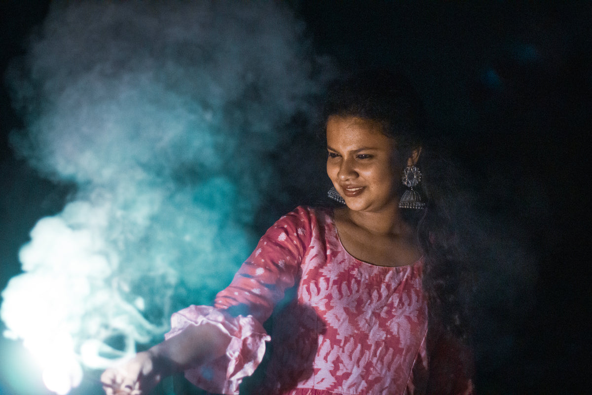 person holds sparkler lit up creating smoke