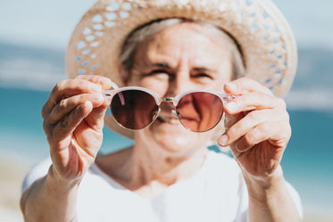 person holds sunglasses out in front of them