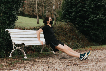 person holds the edge of a bench while stretching