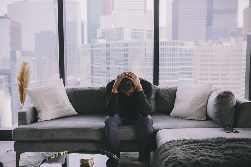 A person sitting on a couch with their head in their hands