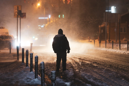 person illuminated by street lights during a snow storm