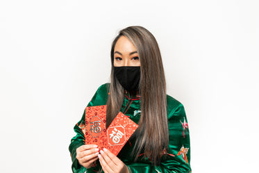 person in a facemask holds red metallic cards