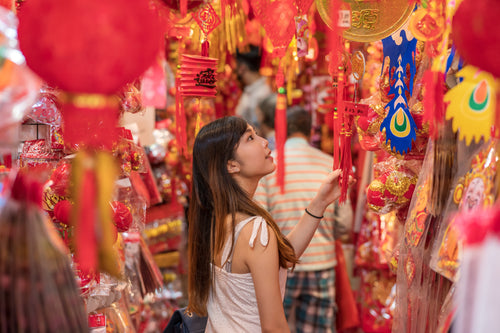 person in a market is surrounded by red and gold items