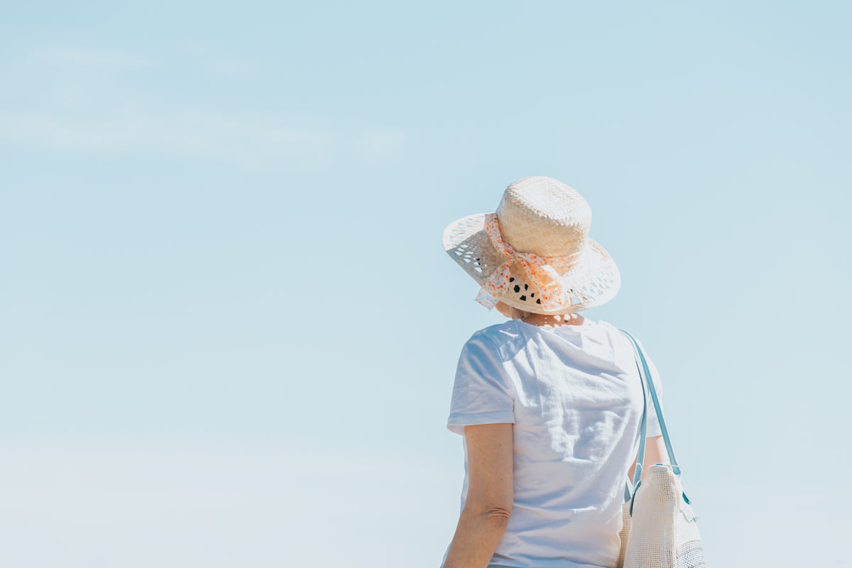 person in a straw hat faces toward a blue sky