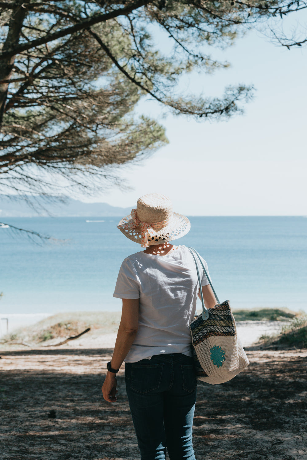 person in a straw hat walks on a bright sandy beach