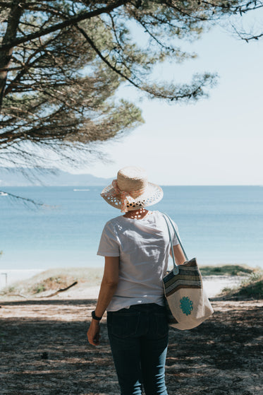 person in a straw hat walks on a bright sandy beach