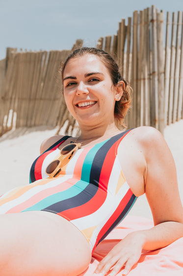 person in a striped bathing suit lays on the beach