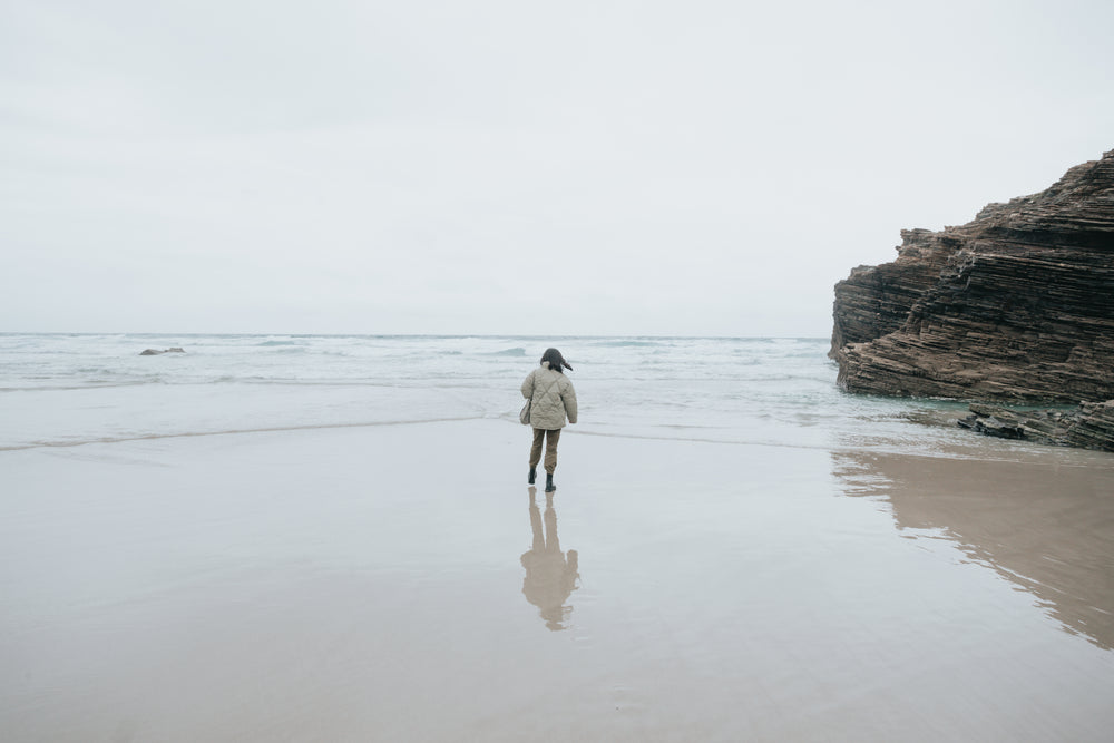 person in a warm jacket looks out to the ocean