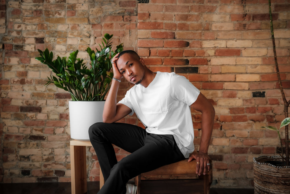 person in a white shirt sits in front of a brick wall