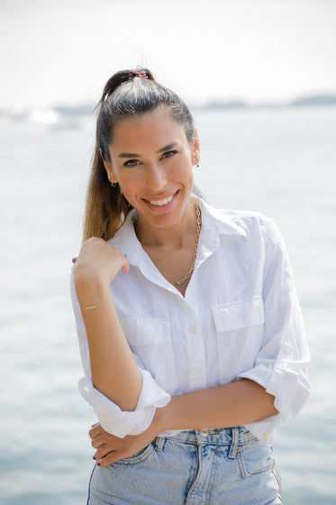 person in a white shirt stands by the water