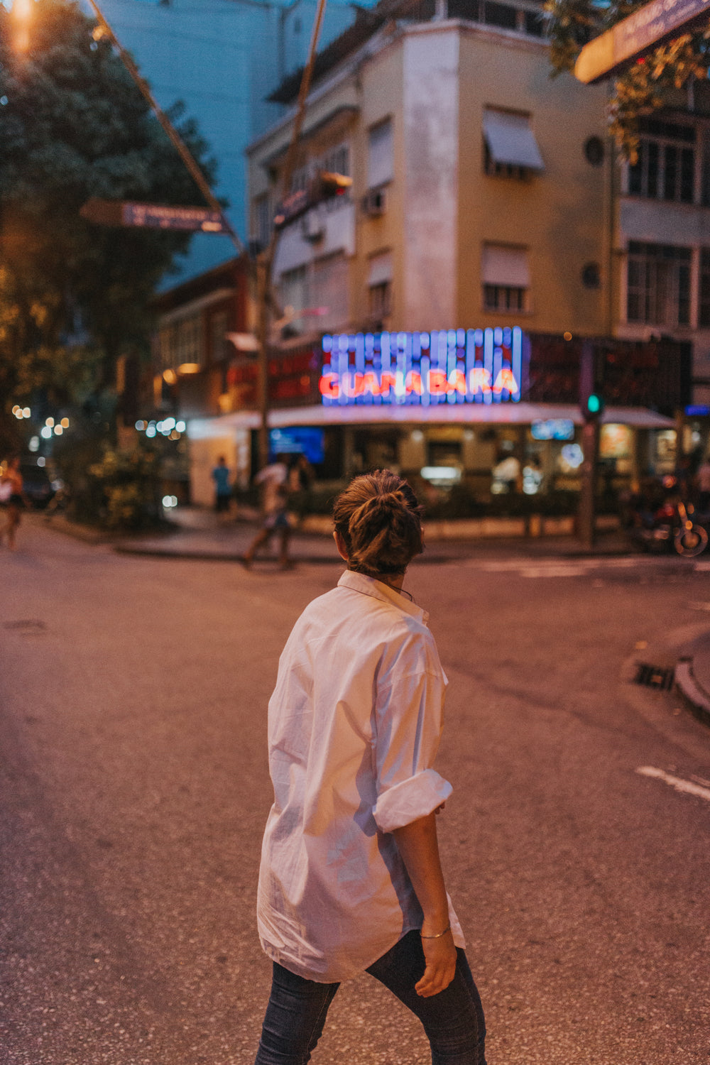 person in a white shirt walks across the street