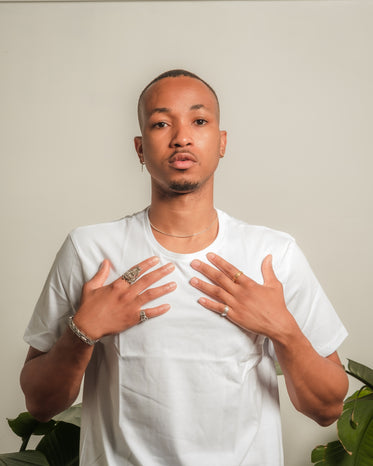 person in a white t shirt holds their hands to their chest