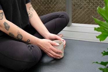 person in athletic wear with a mug with both hands