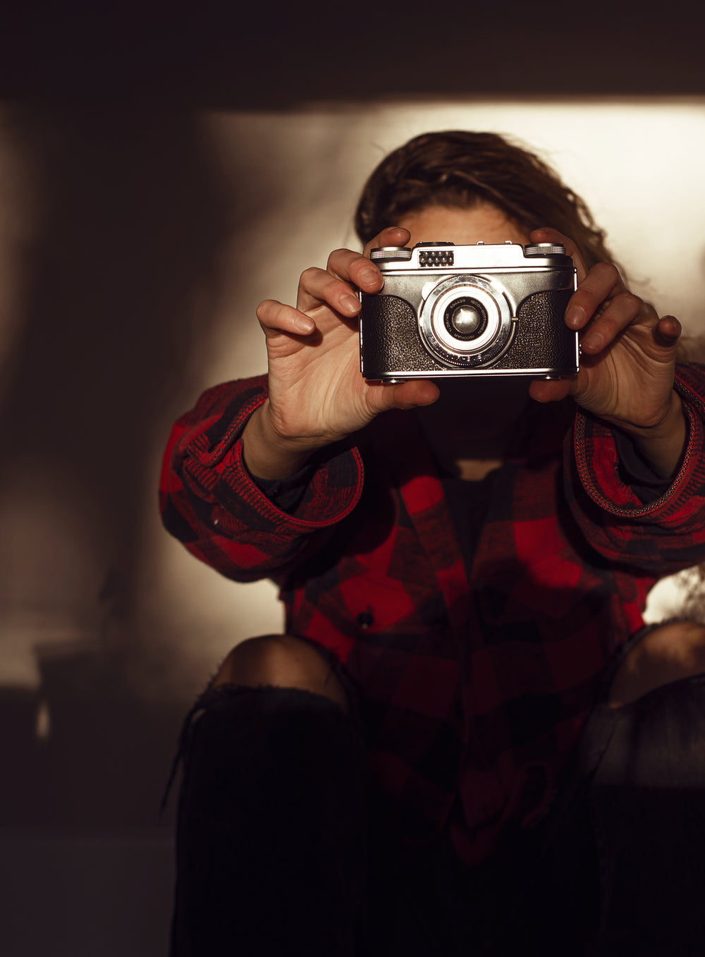 person in black and red holding a camera in front of them