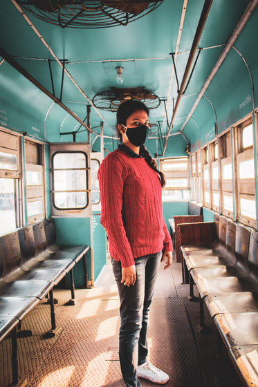 person in black face mask on a blue bus