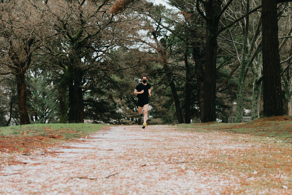 person in black face mask running on dirt path