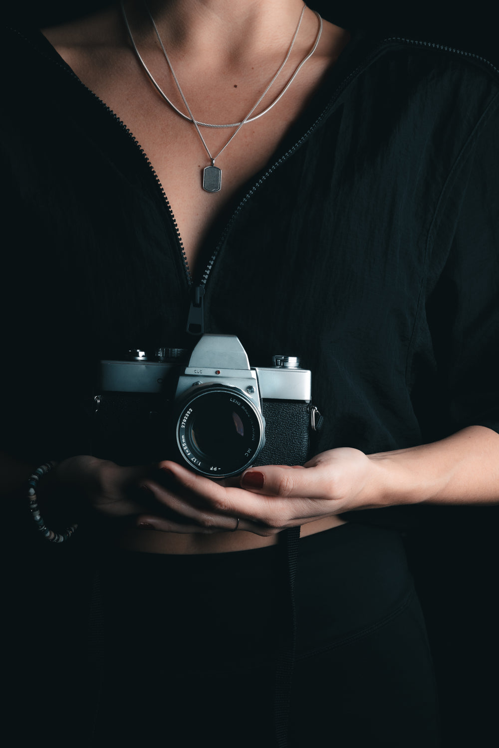 person in black holds camera at their waist