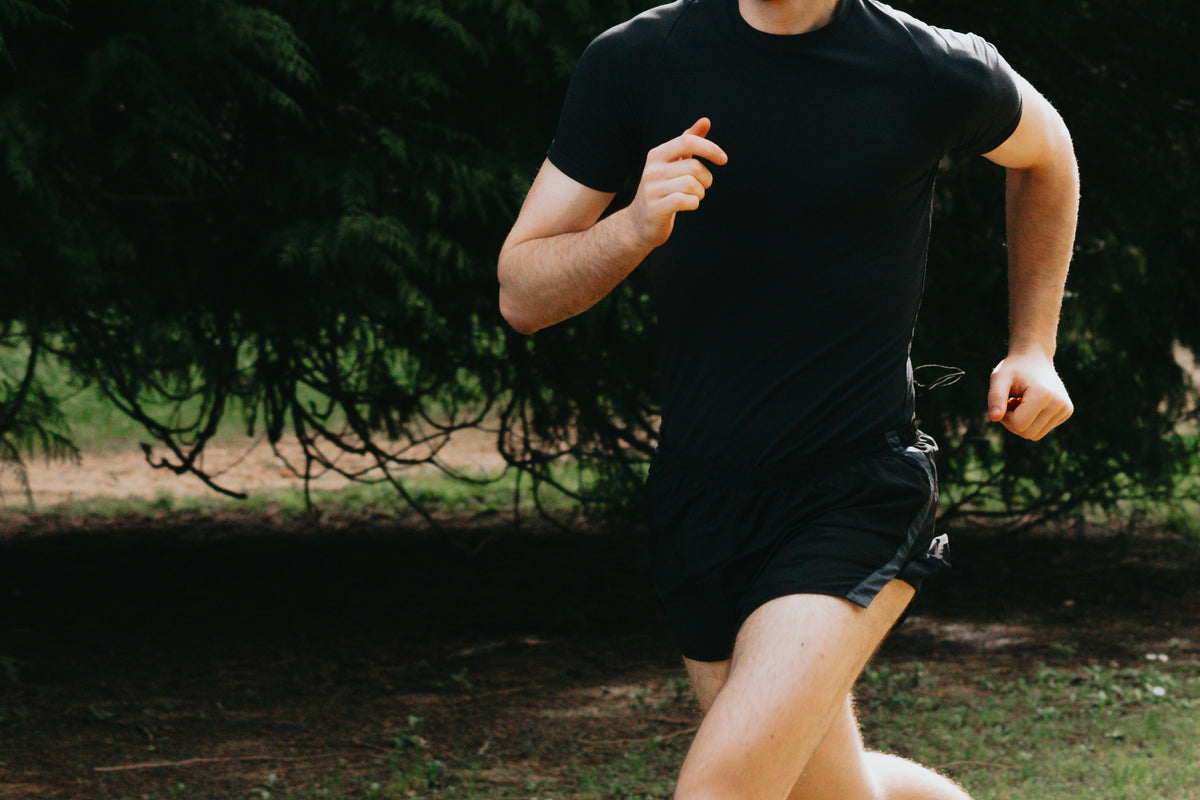 person in black running in the green outdoors