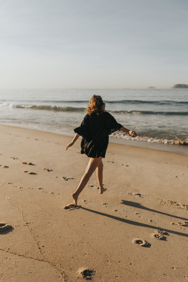 person-in-black-walks-towards-the-water-