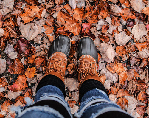 person in boots stand on crunchy fall leaves