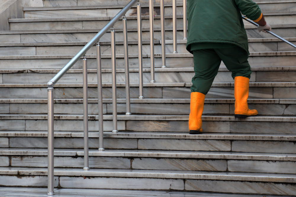 person in green and orange walk up white stone steps