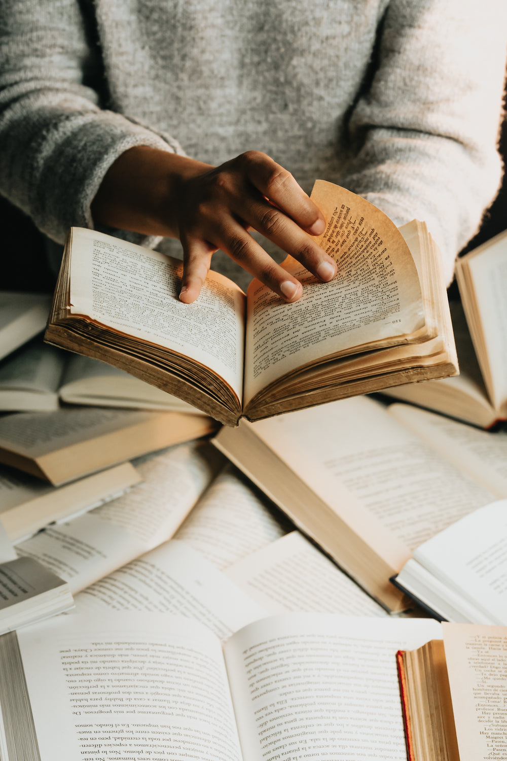 person in grey sweater holds a book open turning the page