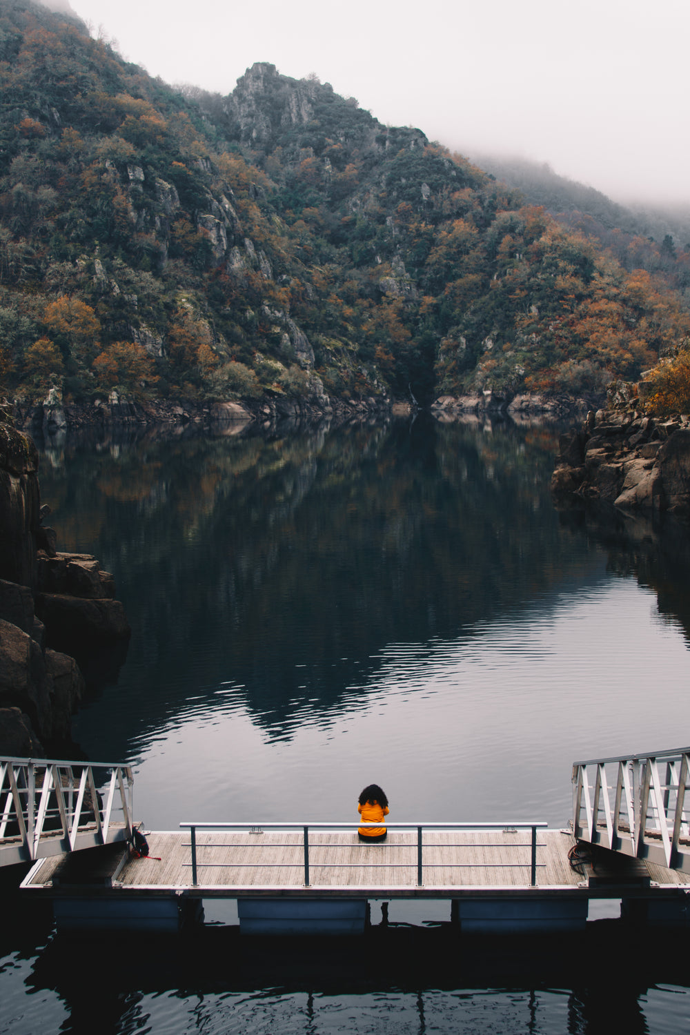 person in orange sits on dock