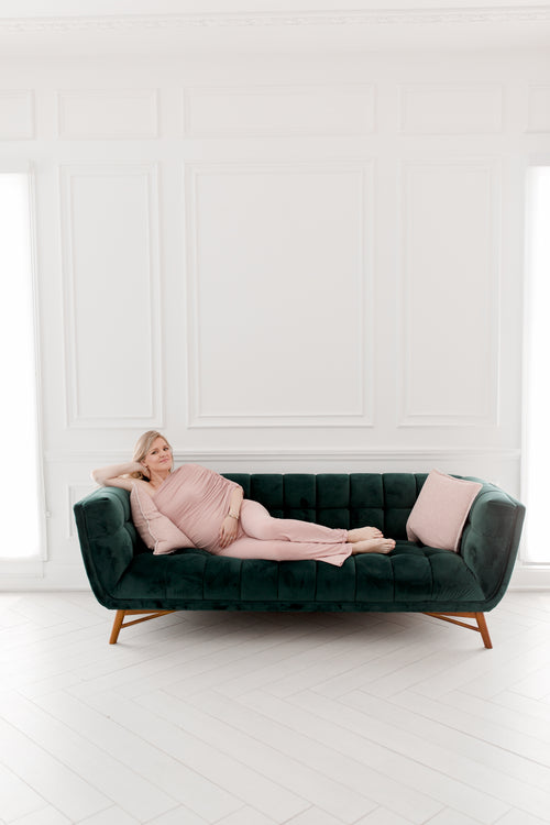 person in pink lays on a green couch
