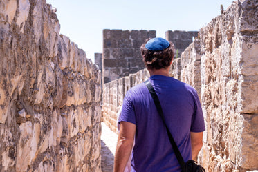 person in purple walks between two stone walls
