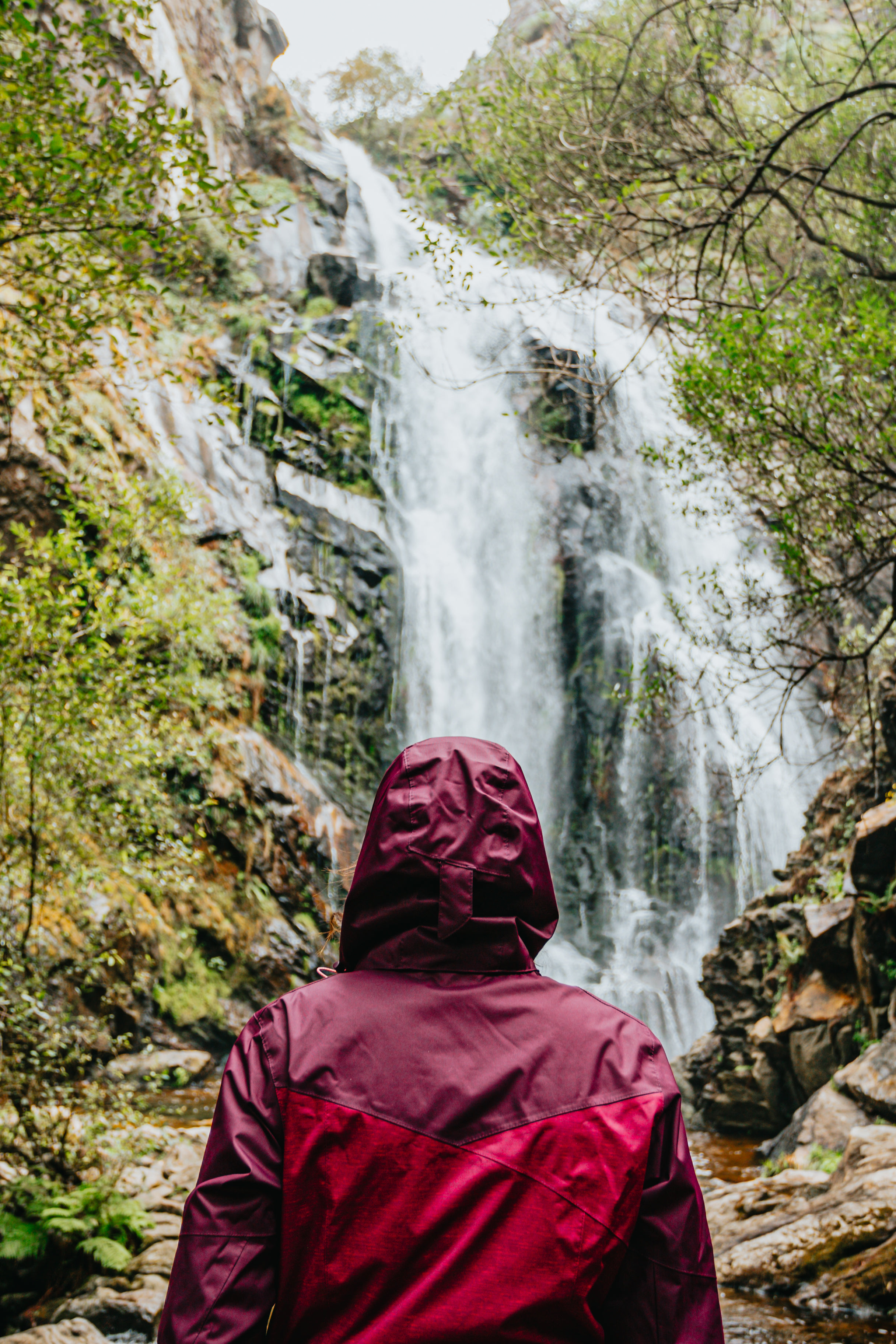 Person In Red Raincoat Admires A Huge Waterfall