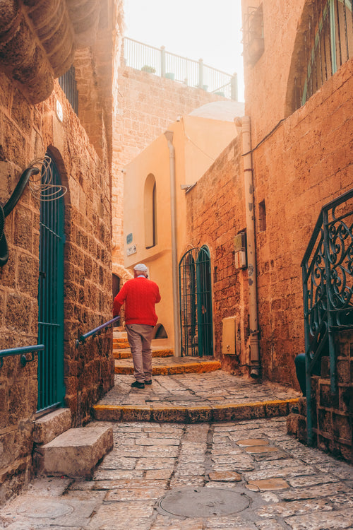 person in red walks down stone alleyway