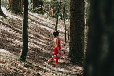 person in red work out wear holds a yoga mat