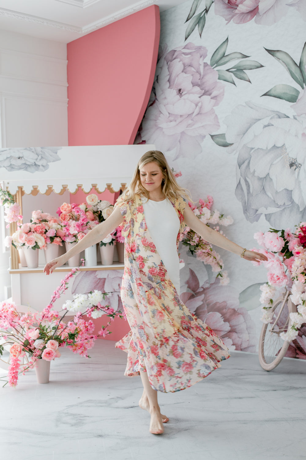 person in white dances in a floral room