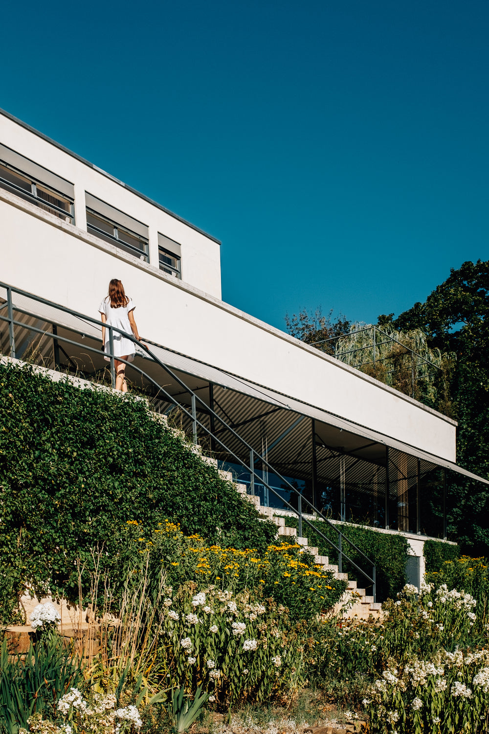 person in white dress stands outside on steps