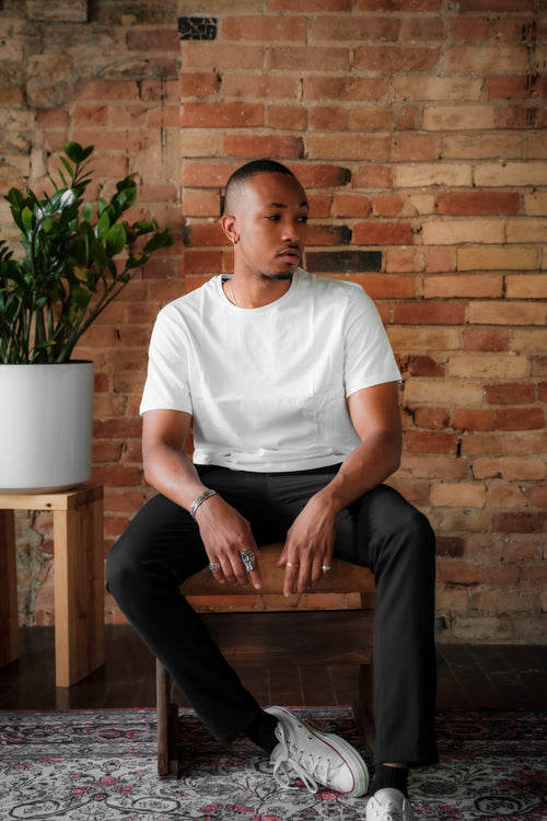 person in white shirt sits against a red brick wall