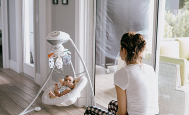 person in white sits looking at their baby