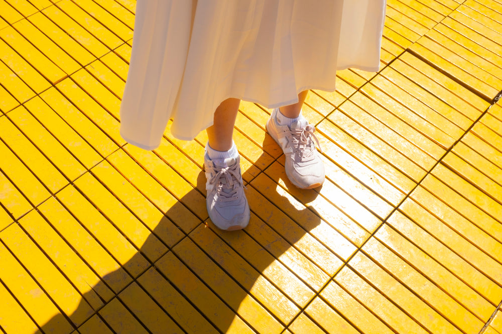 person in white stands on a yellow surface