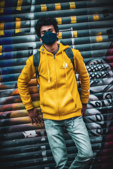 person in yellow leans against graffiti covered wall