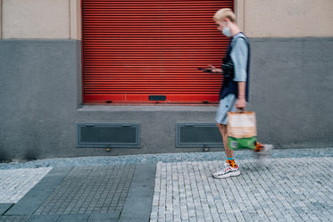 person is blurred as they walk down a sidewalk on their phone