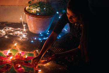 person kneels and lights tealight candles