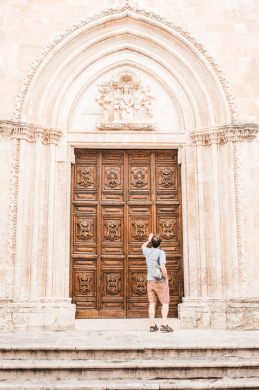 person knocks on large wooden doorway