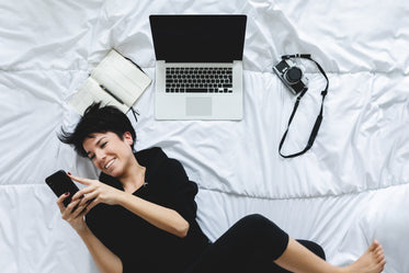 Person Laying On A Duvet And Looking At Their Cell Phone