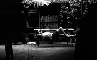 person laying on picnic table in black and white